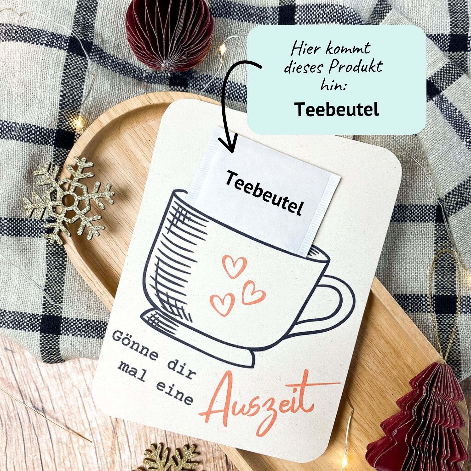 Teebeutel Karte zum Ausdrucken – kleine Auszeit Geschenkidee für Weihnachten DIY Karte mit Tassenmotiv und Spruch „Gönne dir mal eine Auszeit“. In den Schlitz wird ein echter Teebeutel gesteckt. Liegt auf Holzuntergrund mit winterlicher Deko und Lichterkette – kreative Druckvorlage zum Ausdrucken für eine kleine Auszeit oder liebe Geste im Advent.