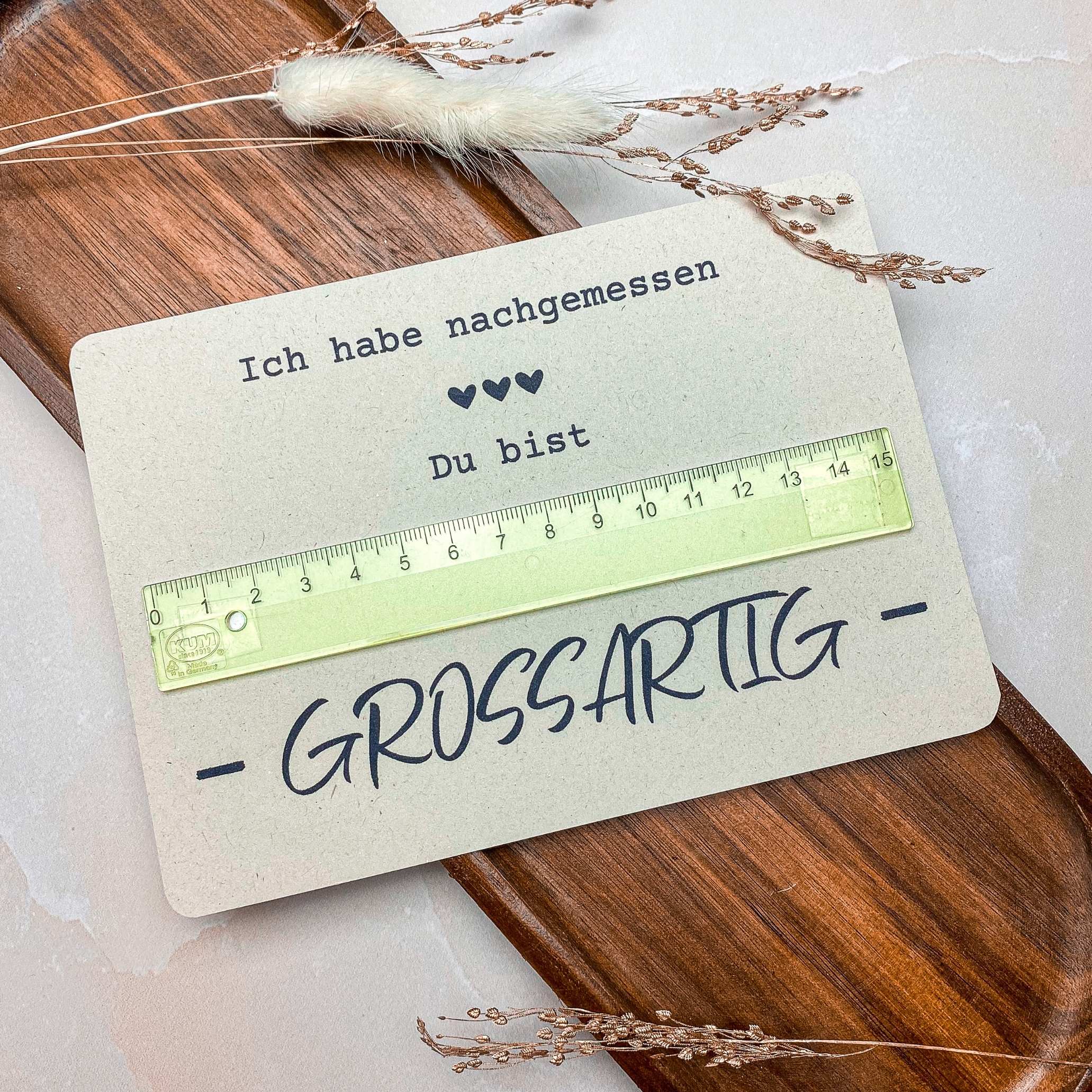 Druckvorlage Karte Lineal Die fertig gebastelte „Du bist großartig“-Karte mit Lineal liegt dekorativ auf einem Holztablett. Ein einfaches und kreatives DIY-Geschenk basierend auf einer digitalen Druckvorlage.