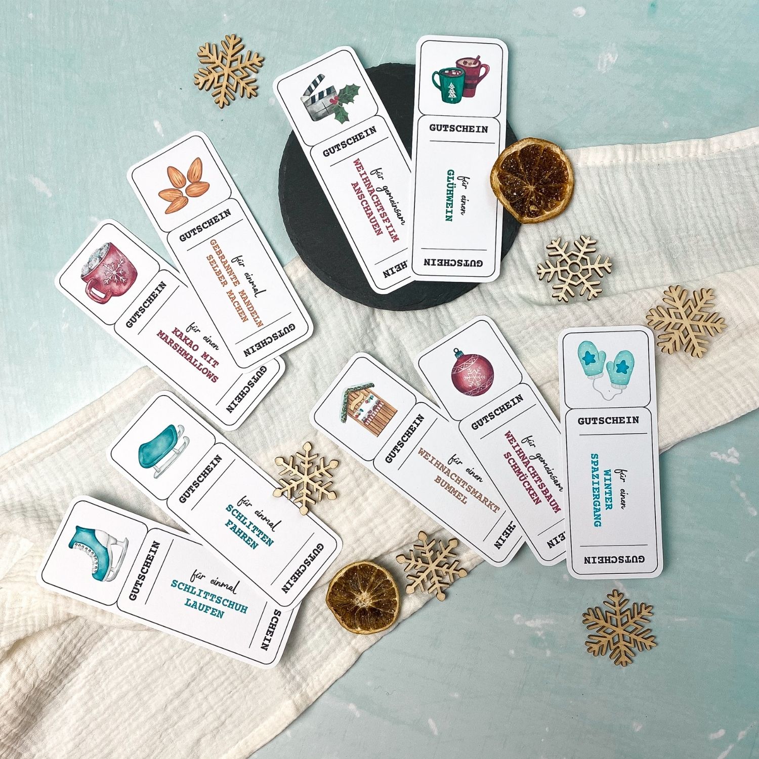 Foto von weihnachtlichen Gutscheinvorlagen zum Ausdrucken, mit Illustrationen von Glühwein, Weihnachtsbaum, Plätzchen, Eislaufschuhen und Kakao. Gutscheine mit Texten wie ‚für einen Glühwein‘, ‚für gemeinsam Weihnachtsbaum schmücken‘ oder ‚für einmal Schlittschuh laufen‘.“